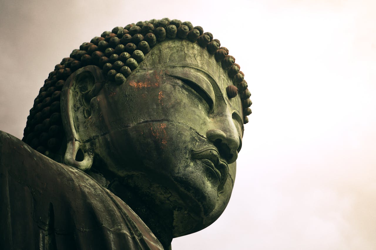 Kodu A serene close-up of a large Buddha statue with a peaceful expression captured from a low angle.