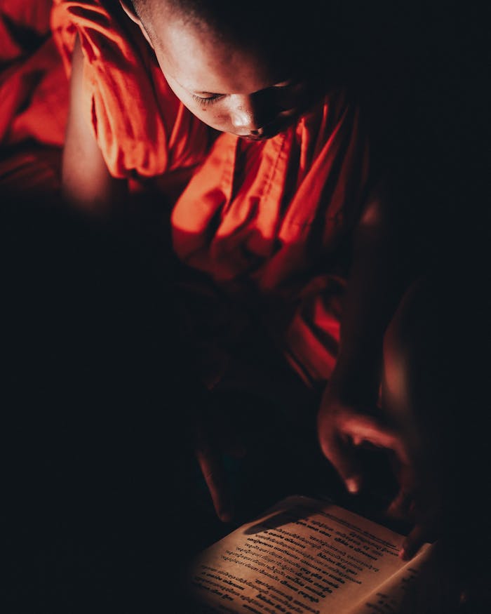 Meist A young monk in Cambodia studies a religious text illuminated by soft candlelight.